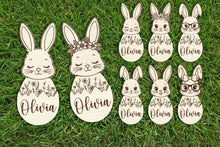 Load image into Gallery viewer, Set of bunny face cutouts with floral designs and the name  on a wooden background.
